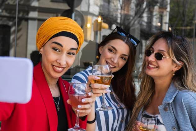 Young woman taking selfie with female friends while having drinks model released Symbolfoto property released PNAF01555