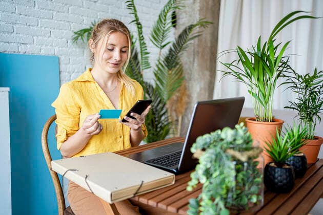 Female professional doing online payment through credit card while sitting at home office model released Symbolfoto property released RCPF01030