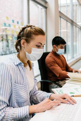 Female professional using laptop by male colleague working in coworking office during pandemic model released Symbolfoto property released XLGF01705
