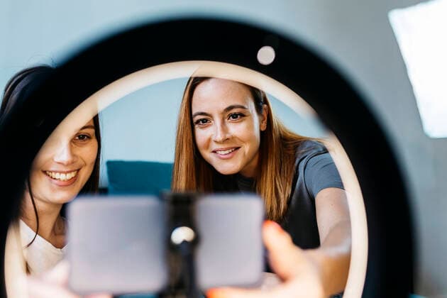 IMAGO Creative: Digitale Welt, Social Commerce Smiling female influencers vlogging using mobile phone at home model released Symbolfoto property released XLGF01733