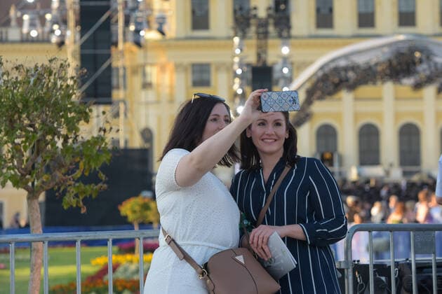 (210619) -- VIENNA, June 19, 2021 -- People take selfies before the Summer Night Concert starts at the Schoenbrunn Palace in Vienna, Austria, June 18, 2021. The Summer Night Concert 2021 was staged on Friday by the Vienna Philharmonic Orchestra at the Schoenbrunn Palace, a world heritage site in Vienna. About 3,000 spectators are allowed to watch the concert face to face after the COVID-19 restrictions were partially lifted. ) AUSTRIA-VIENNA-SUMMER NIGHT CONCERT GuoxChen 
