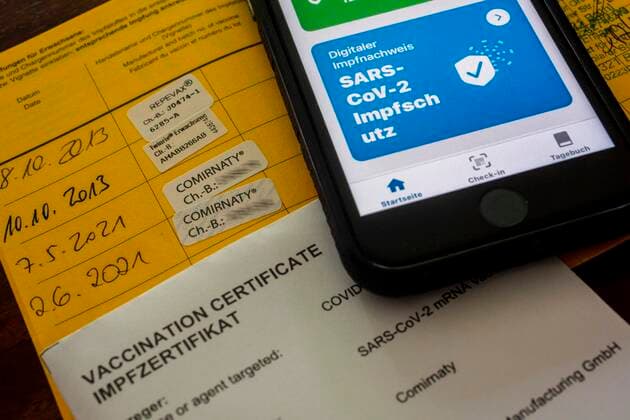 Bescheinigung über eine erfolgte, doppelte Corona-Schutzimpfung im Impfausweis und in der Coronawarnapp auf einem iPhone. Impfzertifikat
