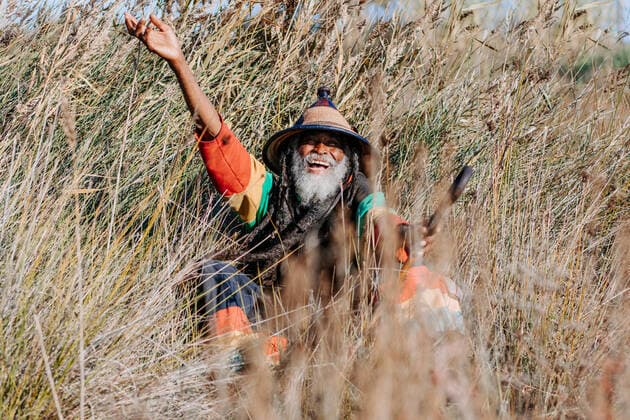 Cheerful old ethnic rastafari with dreadlocks looking at the camera in standing in a dry meadow in the nature, Model released Copyright: xAdrianxSavax MR