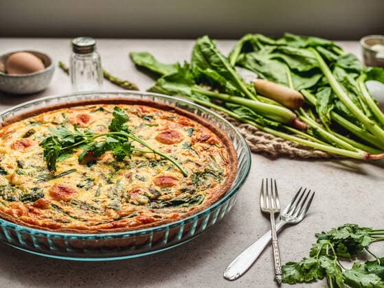 Yummy quiche with parsley placed near egg and fresh spinach with asparagus on table Copyright: xCintiaxViudezx Model Released