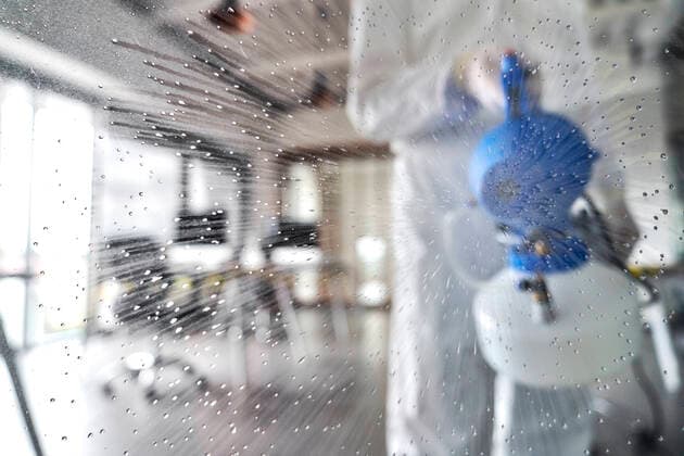 Female sanitation worker splashing disinfecting chemical in office model released Symbolfoto property released ABIF01383