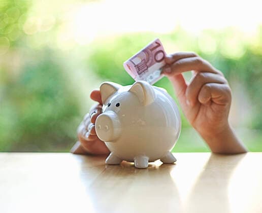 Boy inserting 10 Euro note in piggy bank model released Symbolfoto AJOF01361