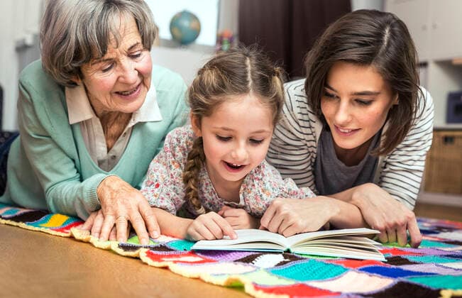Girl reading book while lying by women in nursery model released Symbolfoto property released AUF00636