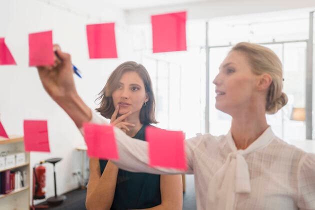 IMAGO Creative, Internationaler Frauenmonat, Entrepreneurinnen IMAGO Creative: Kreative Renaissance -- der junge Entrepreneur Young female entrepreneur looking at coworker writing on adhesive notes while discussing in office model released Symbolfoto property released DIGF15401