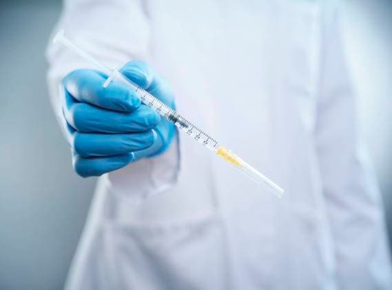 Female doctor holding COVID-19 vaccine model released Symbolfoto DIKF00590