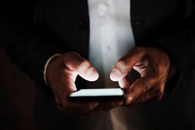 Male entrepreneur using smart phone in dark model released Symbolfoto EBBF04014