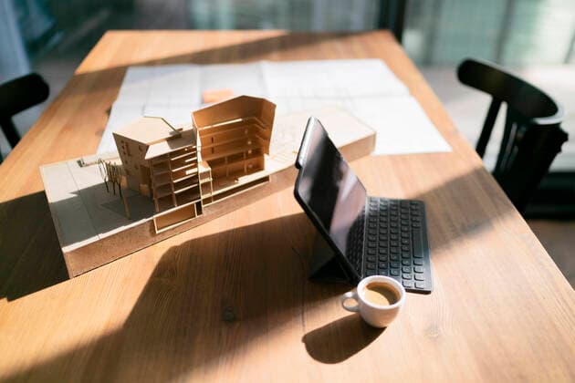 IMAGO Creative: Corporate: Klimaschutz, Digitalisierung und Urbanisierung Laptop with coffee cup and architectural model on table at office property released FKF04346