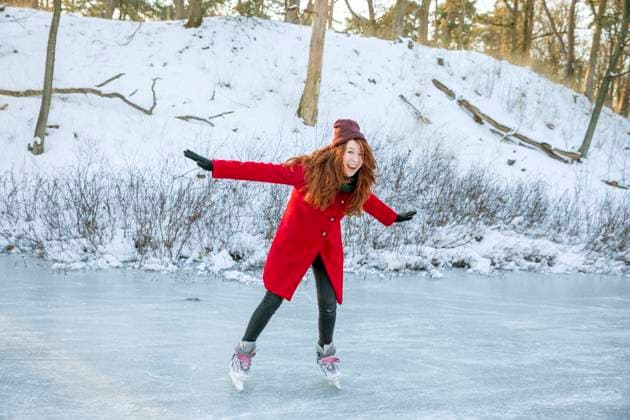 IMAGO Creative, Jahreszeit Winter, Eislaufen Cheerful woman with arms outstretched enjoying ice-skating on frozen lake model released Symbolfoto FVDF00206