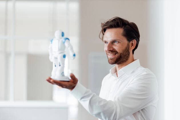 IMAGO Creative: Digitale Welt, Mixed Reality Male entrepreneur holding robot while standing at office model released Symbolfoto property released GUSF05981