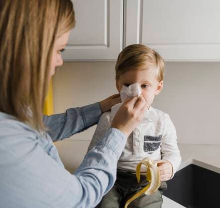 Mother cleaning son s nose at home model released Symbolfoto property released HWHF00023