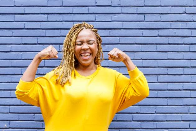 Cheerful plus size woman with eyes closed flexing muscles in front of brick wall model released Symbolfoto IFRF00709