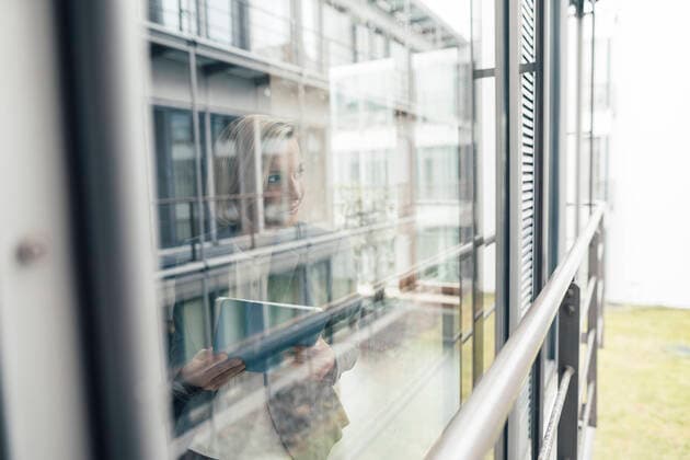 Businesswoman with digital tablet looking through office window model released Symbolfoto property released JOSEF04792
