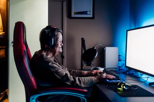 IMAGO Creative: Sport Start-Up Senior woman wearing headphones using computer while sitting at table model released Symbolfoto property released MEUF03132