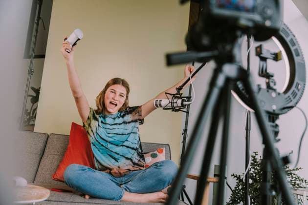 Cheerful girl with arms raised playing game while podcasting at home model released Symbolfoto property released MFF08037