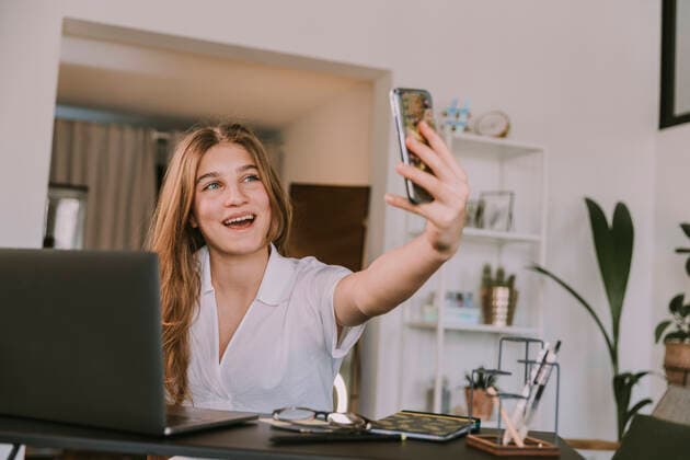 Smiling girl talking on video call through smart phone at home model released Symbolfoto property released MFF08162