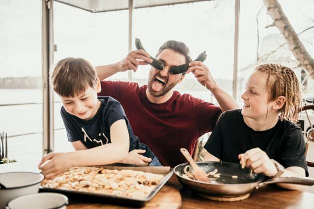 Playful father playing with sons while preparing food in kitchen at houseboat model released Symbolfoto property released MJRF00578