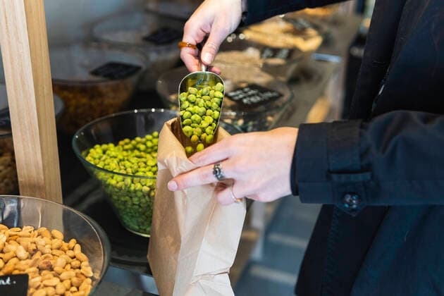 Woman putting green pea in paper bag at store model released Symbolfoto property released PNAF01604
