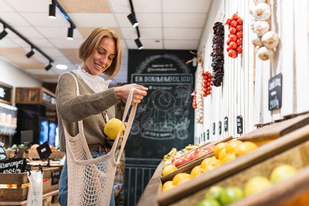 IMAGO Creative: Klimawandel - Zukunft und Innovation Woman collecting fruit in mesh bag while shopping in supermarket model released Symbolfoto property released PNAF01915
