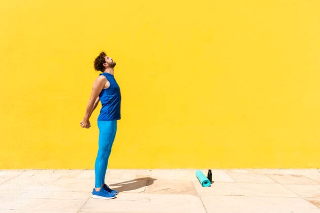 IMAGO Creative: Neue Aussichten Man stretching hands while practicing exercise in front of yellow wall during sunny day model released Symbolfoto RFTF00081