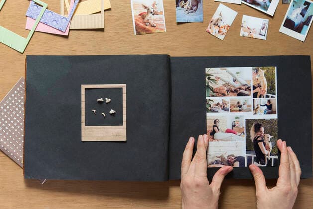 Woman sticking collage photo of dog in scrapbook model released Symbolfoto property released SKCF00741