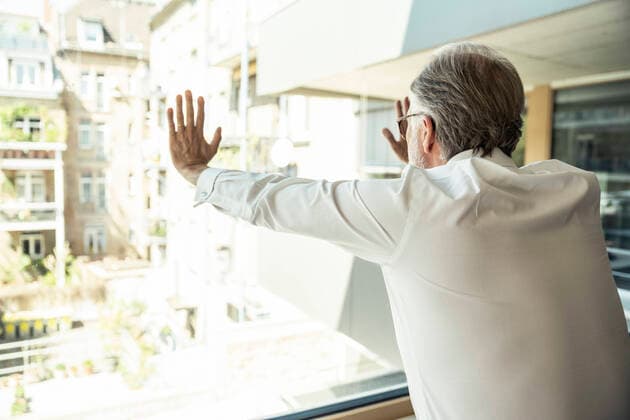Male professional touching glass window while leaning at office model released Symbolfoto property released UUF23486