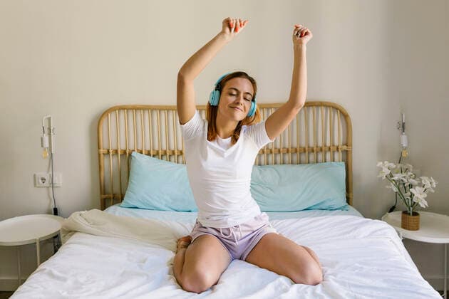 Cheerful woman wearing headphones swaying while listening music at home model released Symbolfoto property released XLGF01904
