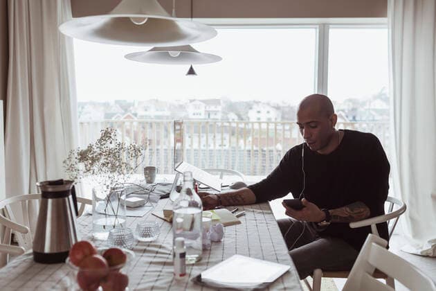 IMAGO Creative: Kreative Renaissance -- der junge Entrepreneur Hispanic male professional using mobile phone while sitting at table in living room Sweden, Gothenburg, model released, property released Copyright: xMaskotx , MA87131
