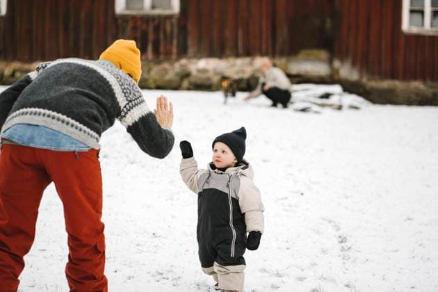 Rear view of mother giving high-five to daughter during winter Sweden, Vastergotland, model released, property released Copyright: xMaskotx , MA87451