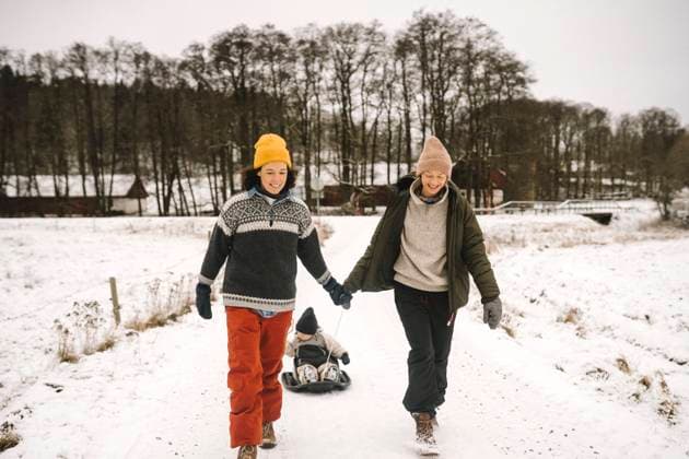IMAGO Creative: Jahreszeit Winter, Spaziergang Smiling lesbian couple pulling daughter on toboggan during winter Sweden, Vastergotland, model released Copyright: xMaskotx , MA87477