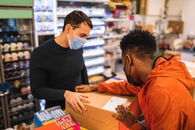 Male entrepreneur and delivery person discussing over package in store Sweden, Gothenburg, model released, property released Copyright: xMaskotx , MA87535