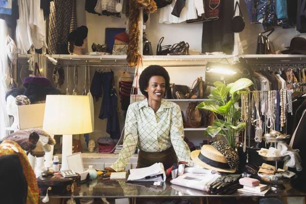 IMAGO Creative: Retro-Revival Smiling female owner looking away while standing at counter in clothing store Sweden, Stockholm, model released, property released Copyright: xMaskotx , MA87715