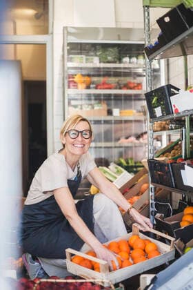 IMAGO Creative: Kreative Renaissance -- der junge Entrepreneur Portrait of smiling female owner arranging fruits in rack at store Sweden, Stockholm, model released, property released Copyright: xMaskotx , MA87770