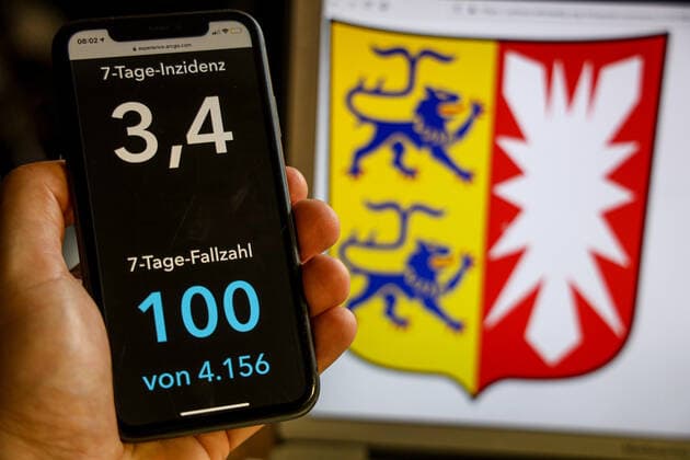 Coronavirus in Deutschland - Covid-19-Dashboard des Robert Koch-Institut DEU, Deutschland, Schleswig-Holstein, 02.07.2021: Die 7-Tage-Inzidenz für das Bundesland (Fälle letzte 7 Tage 100.000 EW) wird auf einem iPhone angezeigt, im Hintergrund das Landeswappen