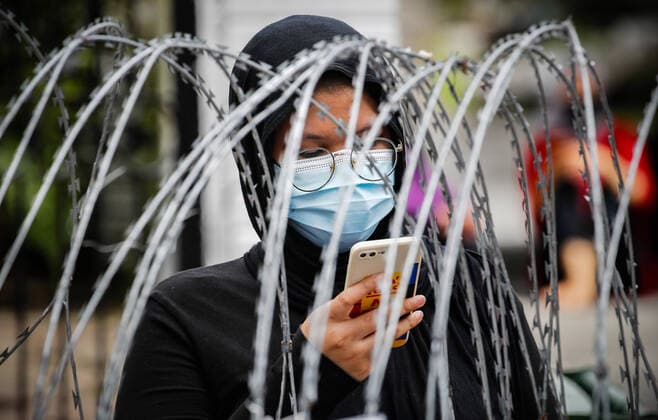 July 3, 2021, Kuala Lumpur, Malaysia: A woman checks her mobile phone as she waits for the Covid-19 swab testing behind the barbwire at the Segambut Dalam housing area which was placed under the enhanced movement control order (EMCO) due to surge in the number of COVID-19 daily cases recorded..Malaysia government starts to further tighten the movement control and imposes lockdown in state of Selangor and parts of Kuala Lumpur, due to the daily high number of coronavirus infections cases reported. Kuala Lumpur Malaysia - ZUMAs197 20210703_zaa_s197_007 Copyright: xWongxFokxLoyx