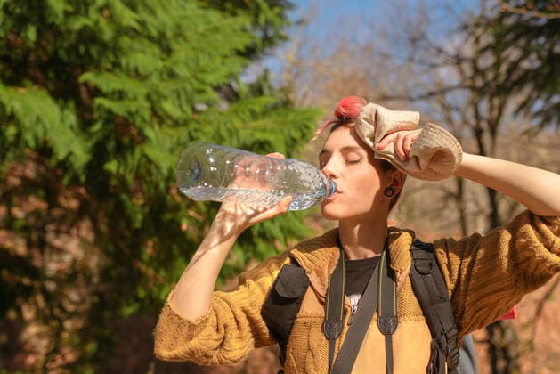 IMAGO Creative, Gesellschaft, Leisure Sickness Thirsty female traveler with backpack enjoying fresh water on sunny day in nature, Model released Copyright: xAlbertoxMenendezx MR