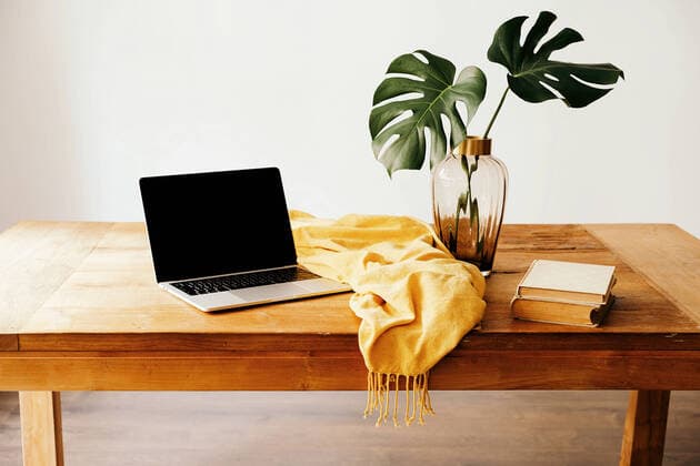 IMAGO Creative: Clickbait, Deko Ideen f?r Zuhause Modern workplace with laptop and books on wooden desk with green foliage in glass vase and yellow cloth against white wall Copyright: xGustavoxPozox Model Released