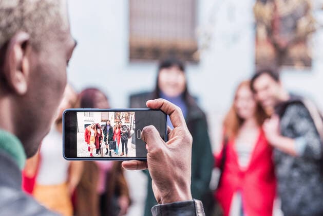 IMAGO Creative: Urban Diversity Back view of unrecognizable black male taking photo of company of multiracial friends standing on street together Copyright: xIvanxMorenox Model Released