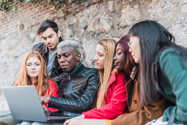 IMAGO Creative: Urban Diversity Company of diverse students doing homework together while using netbook in city street Copyright: xIvanxMorenox Model Released