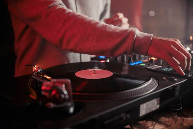 Side view of crop male DJ mixing music on controller during concert in dark nightclub, Model released Copyright: xPabloxGallardox MR