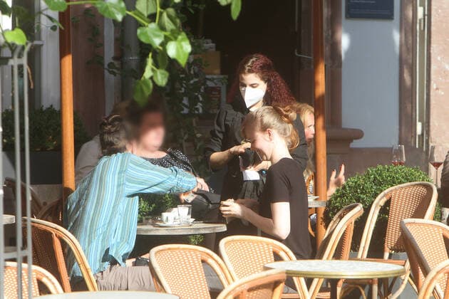 Eine Kellnerin eines Restaurants in der Innenstadt von Heidelberg kassiert die Zeche an einem vollen Tisch, Baden Württemberg, Deutschland