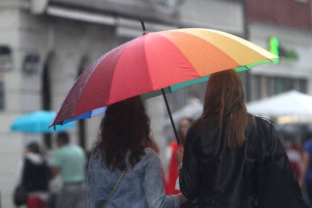 Personen gehen mit Regenschirm während eines Regenschauers in der Innenstadt von Heidelberg, Baden Württemberg, Deutschland