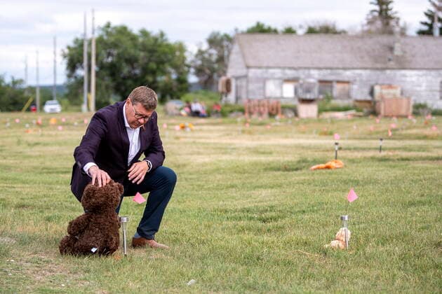 July 6, 2021, Cowessess First Nation, SK, Canada: Saskatchewan Premier Scott Moe lays a teddy bear at a small flag in a field prior to a ceremony at the site of a former residential school where, last month, ground-penetrating radar detected a potential 751 unmarked graves, in Cowessess First Nation, Sask., Tuesday, July 6, 2021. Cowessess First Nation Canada - ZUMAc35_ 20210706_zaf_c35_091 Copyright: xLiamxRichardsx