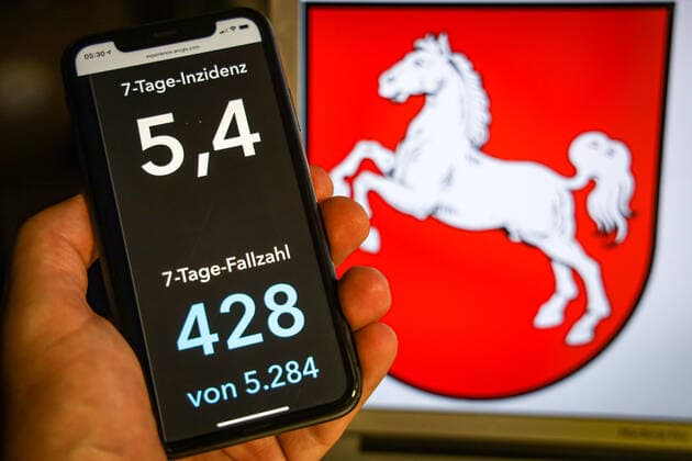 Coronavirus in Deutschland - Covid-19-Dashboard des Robert Koch-Institut DEU, Deutschland, Niedersachsen, 12.07.2021: Die 7-Tage-Inzidenz für das Bundesland (Fälle letzte 7 Tage 100.000 EW) wird auf einem iPhone angezeigt, im Hintergrund das Landeswappen