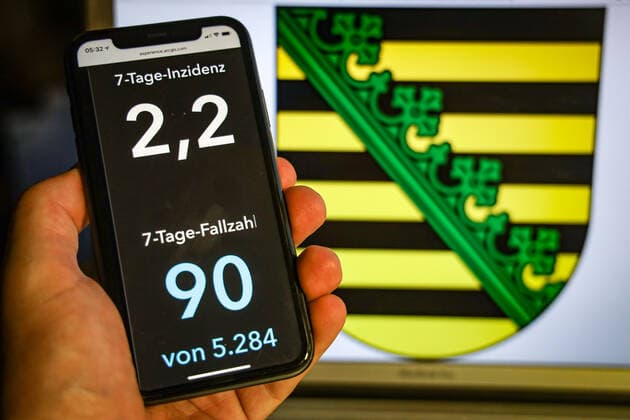 Coronavirus in Deutschland - Covid-19-Dashboard des Robert Koch-Institut DEU, Deutschland, Sachsen, 12.07.2021: Die 7-Tage-Inzidenz für das Bundesland (Fälle letzte 7 Tage 100.000 EW) wird auf einem iPhone angezeigt, im Hintergrund das Landeswappen
