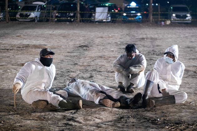 July 11, 2021, Jakarta, Indonesia: Gravediggers wearing personal protective equipment take a break during the burial of a covid-19 victim at Rorotan public cemetery..Indonesia has the highest COVID-19 death toll in South East Asia with 66,464 victims as recorded by the National Disaster Mitigation Agency. Jakarta Indonesia - ZUMAs197 20210711_zaa_s197_575 Copyright: xWisnuxPrasetyox