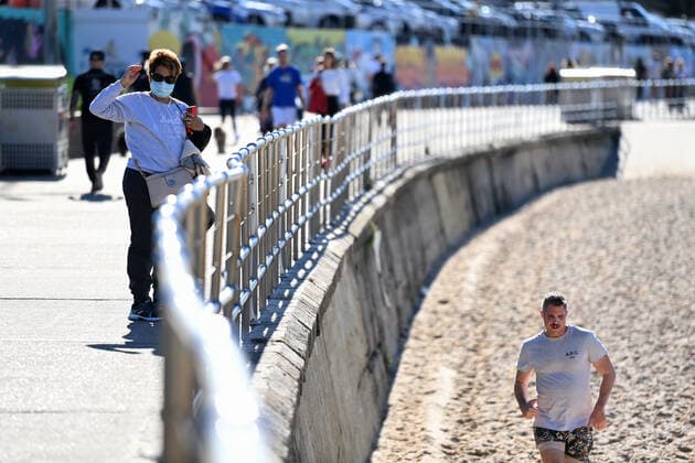 NSW CORONAVIRUS COVID19, A woman wearing a face mask walks along Bondi Beach in Sydney, Thursday, July 15, 2021. New South Wales has recorded 65 new locally transmitted coronavirus cases overnight, 28 of which were infectious during their time in the community. ( NO ARCHIVING, EDITORIAL USE ONLY, NO USE IN BOOKS WITHOUT CONSENT SYDNEY NSW AUSTRALIA  Copyright: xBIANCAxDExMARCHIx 20210715001557395864